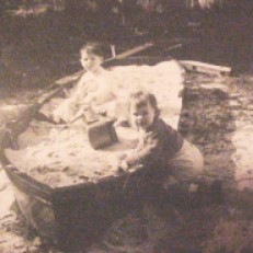 cir 1957 Playing in an old fishing boat that belonged to Ed Morris, Kevin Cooper and Tenderly Rose enjoy the sand in the re-purposed john boat. The boat's final resting place was Rosie and John Morris's home at 1711 Wisteria Street in Gulfport, Mississippi (Gulf Gardens).